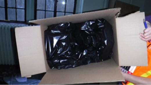 A large cardboard box lined with heavy black plastic is ready to be filled with wet books.