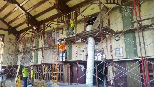 Workers construcing scaffolding along the murals in the Great Room. 