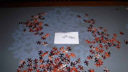 Red puzzle pieces on a dark blue table are scattered around to reveal light blue puzzle shapes left on the table. 