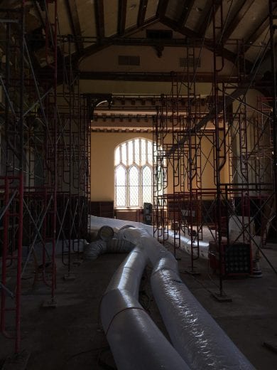 Large plastic tubes and metal scaffolding are back lit by a leaded glass window in the Great Room. 