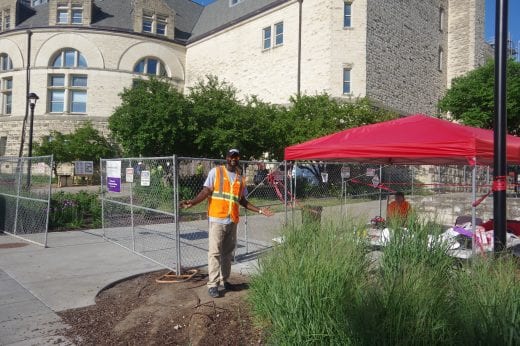 A Belfor worker in an orange vest in front of Hale next to a red tent. 