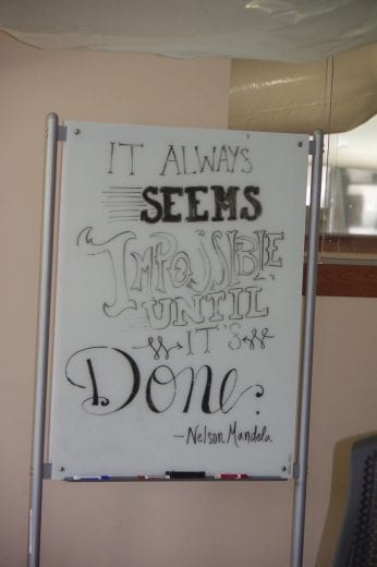 A quote from Nelson Mandela on a white board that reads "It always seems impossible until it's done."