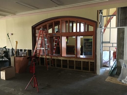 A large wooden cabinet display is being deconstructed by workers.