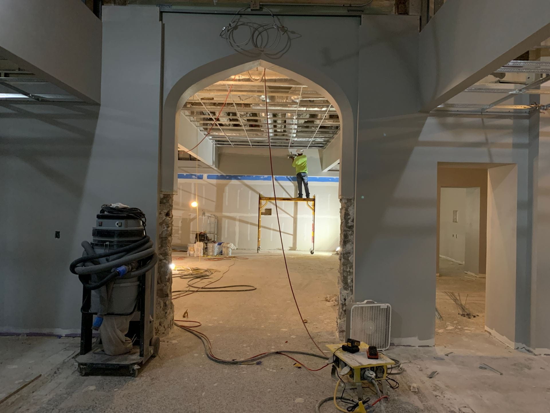 A construction worker is seen on the other side of an arched doorway.