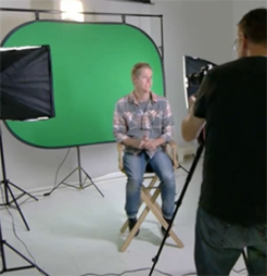 Smaller green screen with male sitting on chair in front of screen