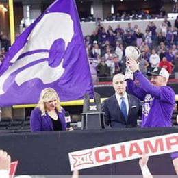 K-State football coach on awards stand holding the Big 12 championship trophy