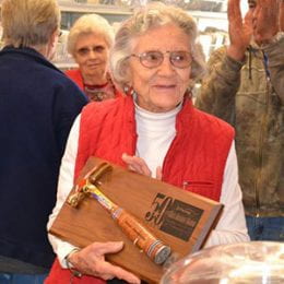 Woman wearing eyeglasses and holding a plaque with hammer attached