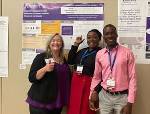 Three PhD students stand in front of their poster presentation